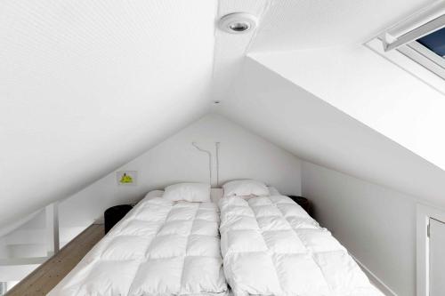 un letto bianco nella soffitta di una stanza di Bornholm Holiday Apartment With Sea View ad Allinge