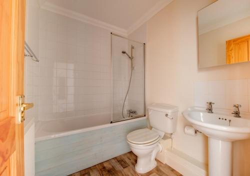 a white bathroom with a toilet and a sink at Scholars Cottage in Reydon