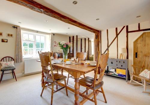 a dining room with a wooden table and chairs at Walnut Tree Cottage in Mildenhall