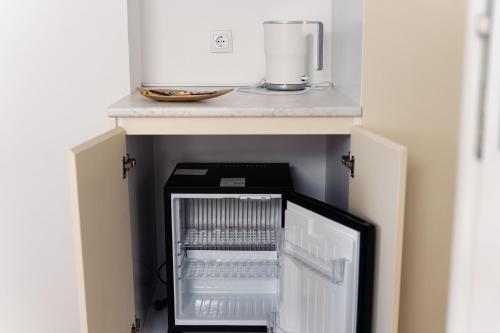 a small refrigerator with its door open in a kitchen at Old Town Rooms in Novi Sad