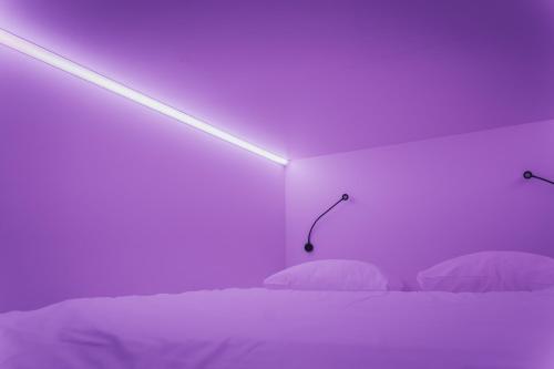 a bedroom with a purple room with a bed and lights at THIS HO(S)TEL in Amsterdam