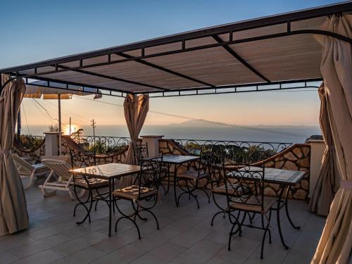 a patio with tables and chairs and a view of the ocean at Casa Astra in Anacapri