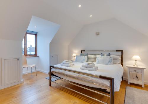 a white bedroom with a large bed with blue pillows at The Cartlodge in Sudbury
