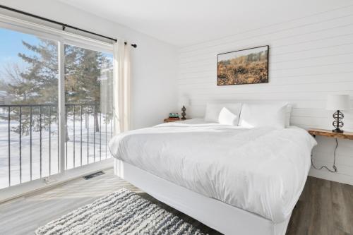 a white bedroom with a bed and a large window at Collingwood Chalet Near Blue Mountain Slopes 39B in Collingwood