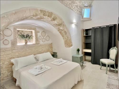 - une chambre avec un grand lit blanc et une chaise dans l'établissement Don Pietro - Pieno Centro Storico, à Ostuni