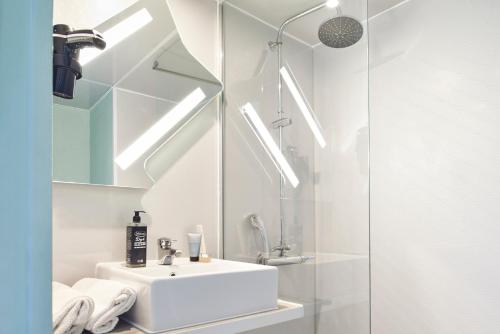 a white bathroom with a sink and a shower at ibis budget Saint-Ouen-l'Aumône in Saint-Ouen-lʼAumône