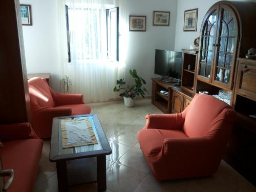 a living room with two red chairs and a tv at Apartment Ranka in Postira