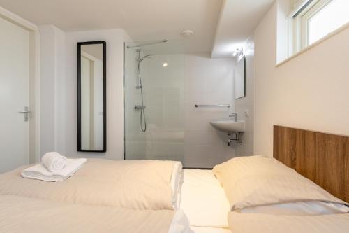 baño con 2 camas, ducha y lavamanos en Strandvilla 30 Renesse, en Renesse