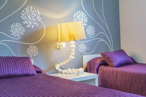 a bedroom with two beds with purple sheets and a lamp at Chalet con Impresionantes vistas en Conil in Conil de la Frontera