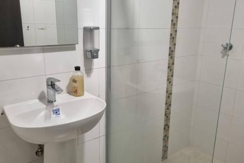 y baño blanco con lavabo y ducha. en Soniella apto - WAIWA HOST, en Bucaramanga