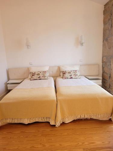 a bedroom with two beds and a stone wall at Alijó Douro House in Alijó