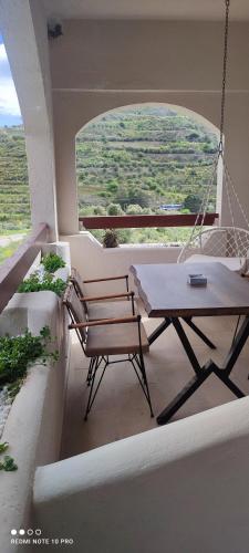 a porch with a swing and a table and a chair at Natural Green Apartment in Dhamnóni