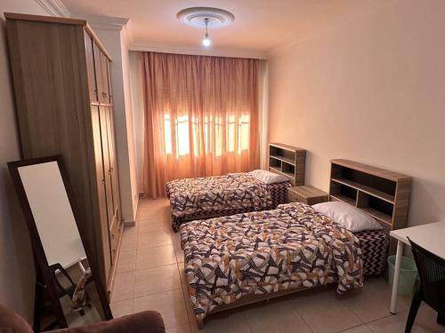 a hotel room with two beds and a window at 4 Bedroom Flat in Madaba with AC in Madaba