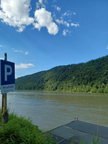 ein Schild vor einem Fluss mit einem Berg in der Unterkunft Gasthaus zur blauen Donau in Wesenufer