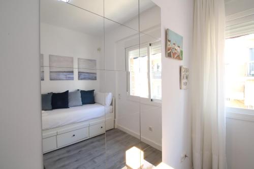 Una habitación blanca con una cama y un espejo. en Del Parque Flats Candelaria Sea View, en Rincón de la Victoria