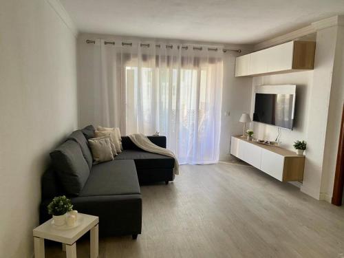 a living room with a black couch and a television at Beautiful refurbished apartment Duquesa port in Casares