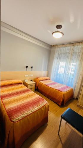 a hotel room with two beds and a table at Hostal Hispanico I in Salamanca