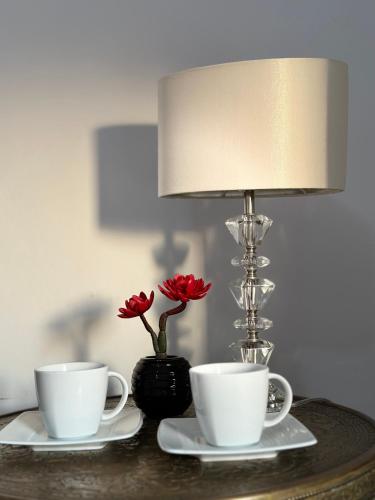 two coffee cups and a lamp on a table at Pensjonat Jagoda B&B in Międzyzdroje