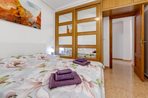a bedroom with a bed with purple towels on it at Penthouse CORBETA SUN in Torrevieja