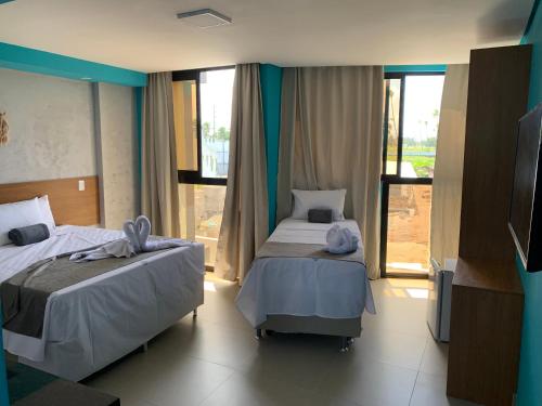 a hotel room with two beds and a television at Pousada Atlantic in Porto De Galinhas