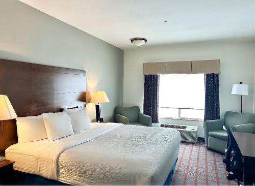 a hotel room with a bed and chairs and a window at La Quinta by Wyndham Bozeman in Bozeman