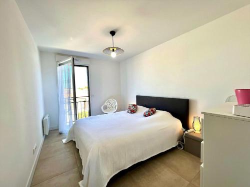 a bedroom with a white bed and a window at Appartement Mèze, 3 pièces, 4 personnes - FR-1-604-37 in Mèze