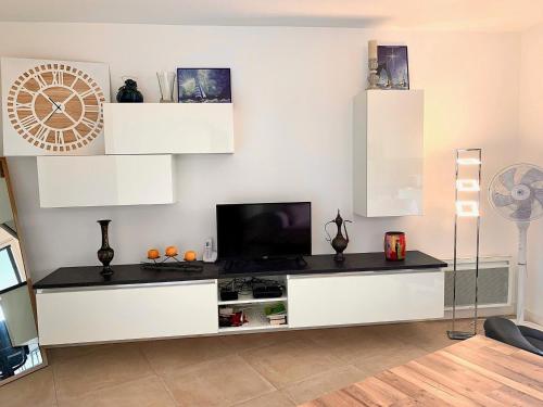 - un salon avec une télévision sur un meuble blanc dans l'établissement Appartement Standing avec Terrasse Vue Étang, 2 chambres et WIFI - Mèze - FR-1-604-37, à Mèze