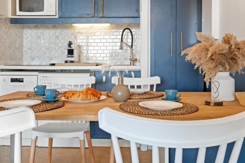 cocina con mesa de madera y armarios azules en Sea Breeze Retreat, en Cap d'Ail