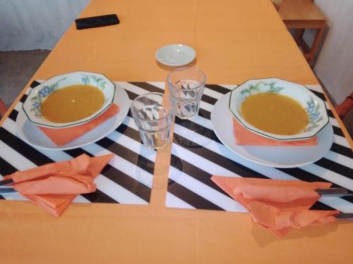 a table with two bowls of soup and two glasses at Pousada Cantinho de Preta in Seladinha