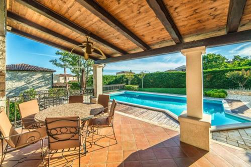 a patio with a table and chairs and a swimming pool at Vila Romana in Barat