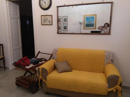 a yellow couch in a living room with a mirror at Casa Sofia: comodi e tranquilli in Maruggio