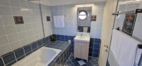 a blue tiled bathroom with a tub and a sink at Beachlife: The Apartment in Marmari