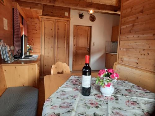 a bottle of wine sitting on a table with a vase of flowers at Weiherhütte Ried in Ried im Oberinntal