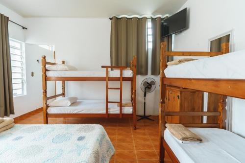 a room with three bunk beds in a house at Pousada Vista da Pedra in São Bento do Sapucaí