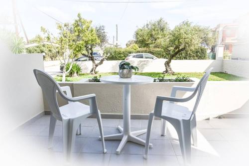 een witte tafel en 2 stoelen op een balkon bij Stacy's Studios in Kremasti