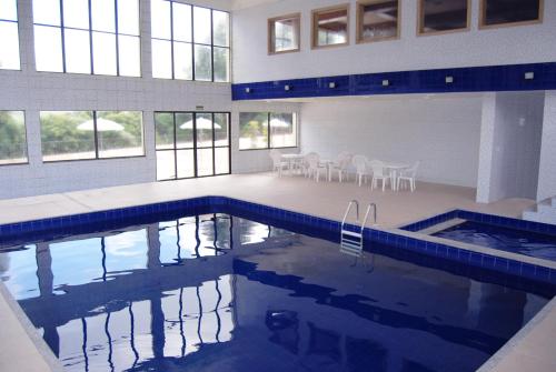 uma piscina com cadeiras e mesas num edifício em Sky Samuara Hotel Caxias do Sul em Caxias do Sul