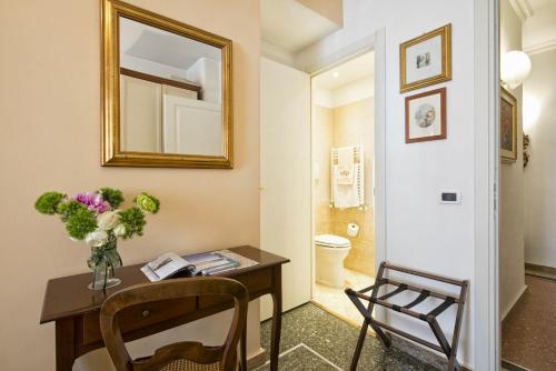 een badkamer met een tafel met een vaas met bloemen en een spiegel bij B&B Le Sibille in Rome