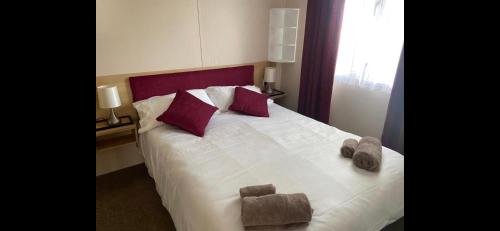 a bedroom with a large white bed with purple pillows at Home by the sea, Hoburne Naish Resort, sleeps 4, on site leisure complex available in Milford on Sea