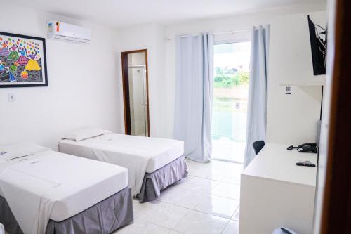una camera d'albergo con due letti e una finestra di Belaris Hotel antes Hotel Costa do Calhau a São Luís