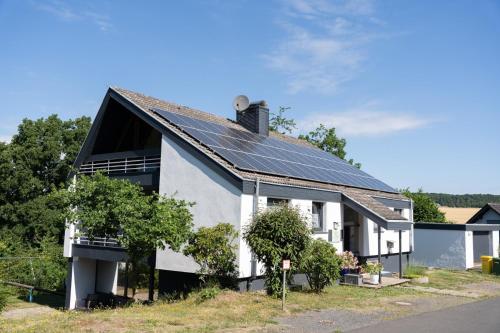 a white house with solar panels on the roof at Ferienhaus Schöne Aussicht Ferienwohnung Blau in Hemfurth-Edersee