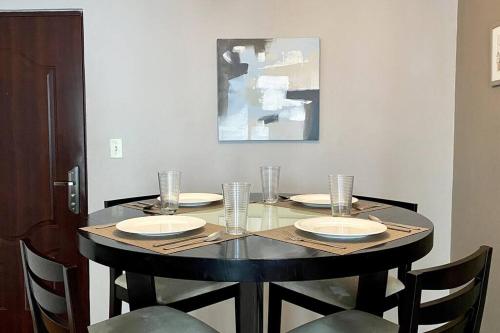 un tavolo con quattro sedie e un tavolo con piatti e bicchieri di Apartamento con excelente ubicación! Hasta 4 Personas a Città di Panama