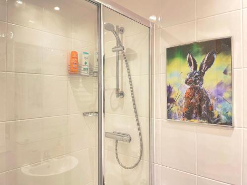baño con ducha y una pintura de un conejo en Natural Studio by HNFC Stays en Newcastle