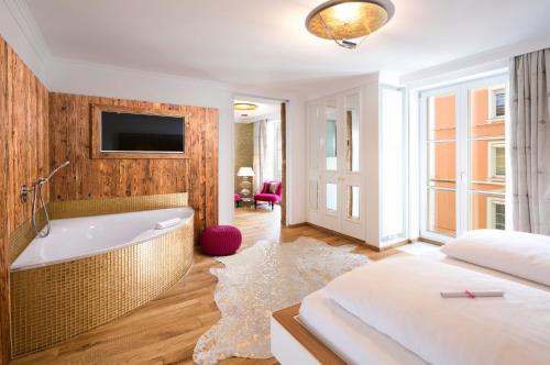a bedroom with a tub and a bed and a tv at YachtHotel Helvetia Spa- und Wellnessdomizil in Lindau
