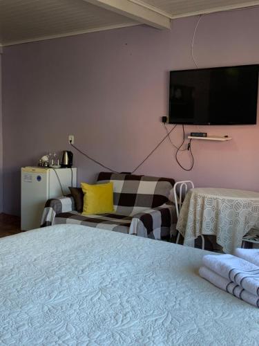 um quarto com uma cama, um sofá e uma televisão em Pousada Simone em Cambará