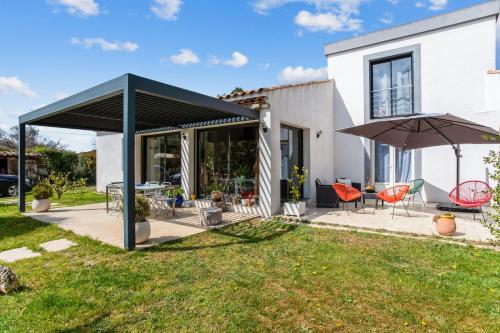 patio z parasolem, stołem i krzesłami w obiekcie Villa Massilia - Welkeys w mieście Aubagne