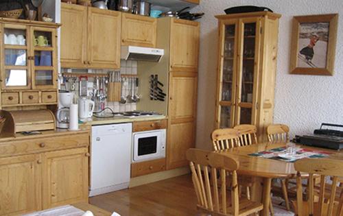 une cuisine avec des armoires en bois et une table avec des chaises dans l'établissement Les Gets Le Grand Paradis, aux Gets