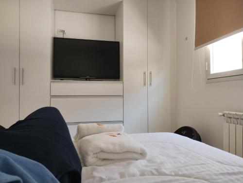1 dormitorio con TV y 1 cama con toallas en Quilimbai Departamentos Turísticos en Malargüe