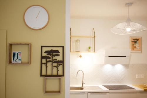 eine Küche mit einem Waschbecken und einer Uhr an der Wand in der Unterkunft * Seignosse * Plage * Forêt * Couple * Famille in Seignosse