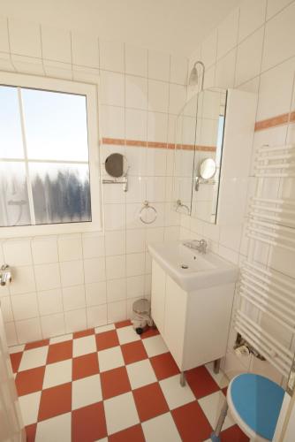 a bathroom with a sink and a toilet and a window at Haus Albatros in Dorum-Neufeld