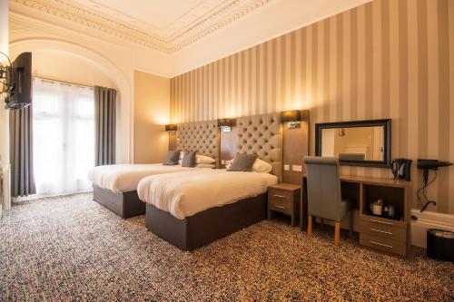 a bedroom with two beds and a desk and a mirror at Embassy Apartments in Glasgow